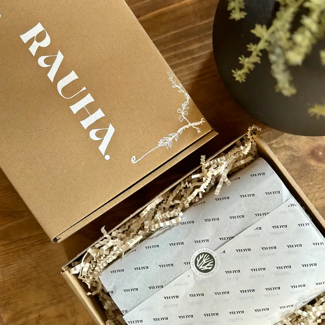 Caja de embalaje de Rauha abierta mostrando el contenido con papel de seda y relleno decorativo.